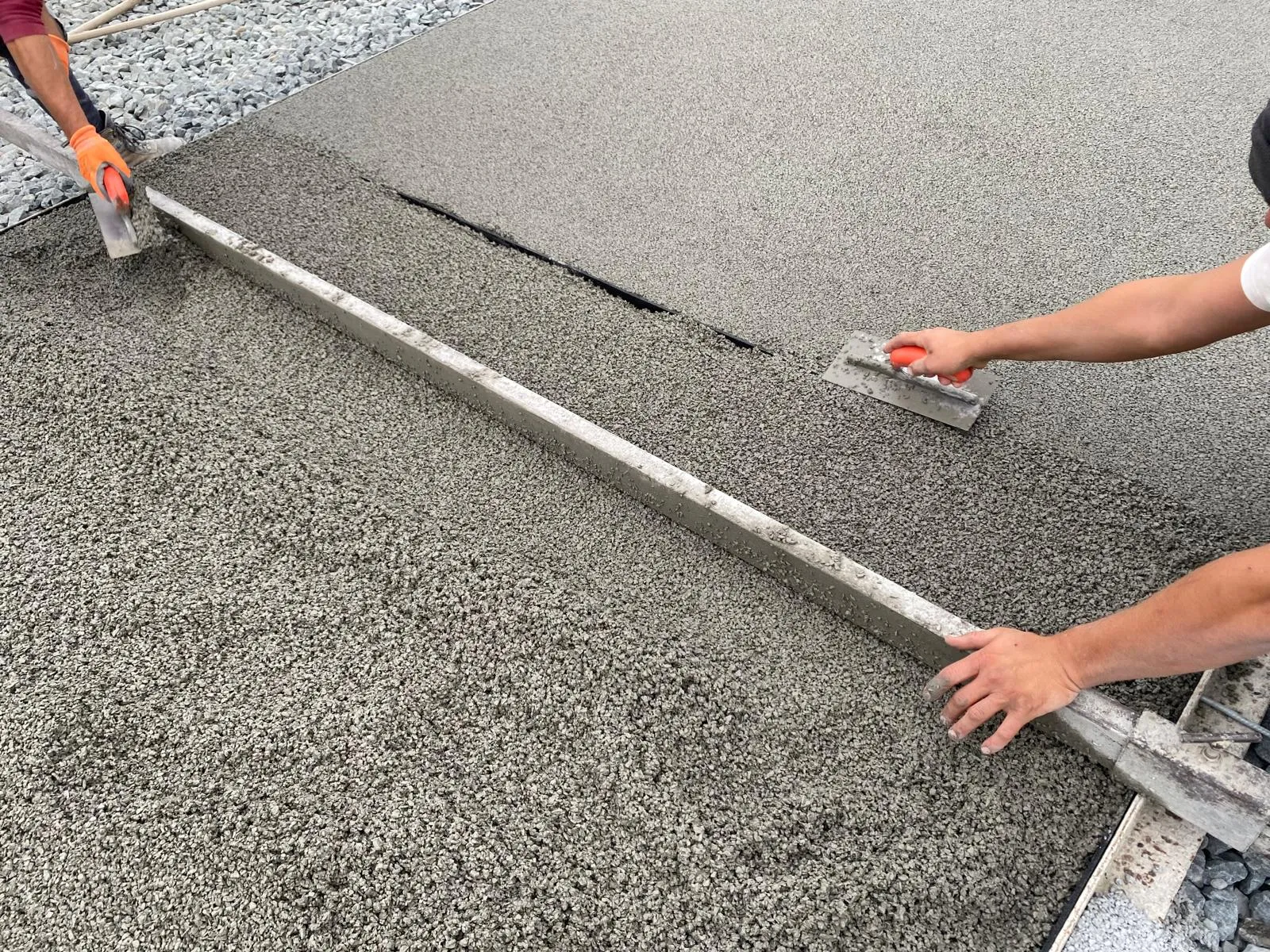 Pose des revêtements sur un court de tennis rénové en béton poreux avec les rouleaux prêts à être installés.