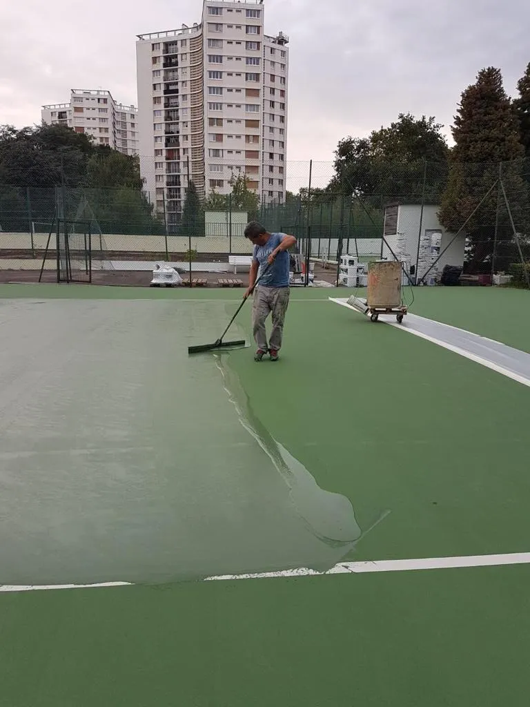 Application de résine sur un terrain de tennis extérieur en pleine rénovation