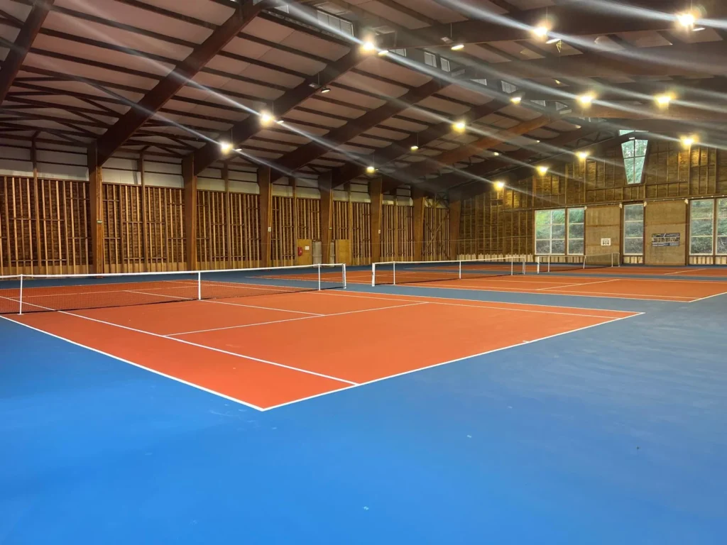 Terrain de tennis intérieur en résine acrylique après rénovation avec surface professionnelle