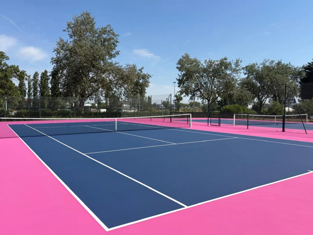 Court de tennis en résine après régénération à Tours : aire de jeu bleu foncé, pourtour rose et lignes blanches retracées